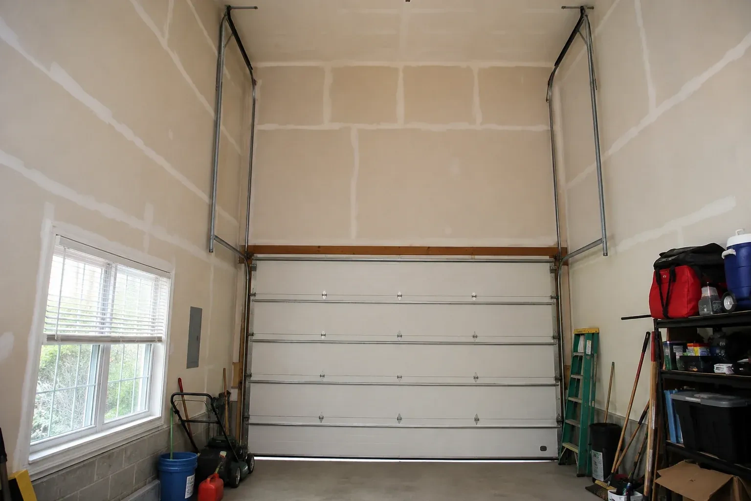 Tall garage interior with a sectional door and tracks extending into overhead space. — High-Lift Garage Door Conversion, Hamilton